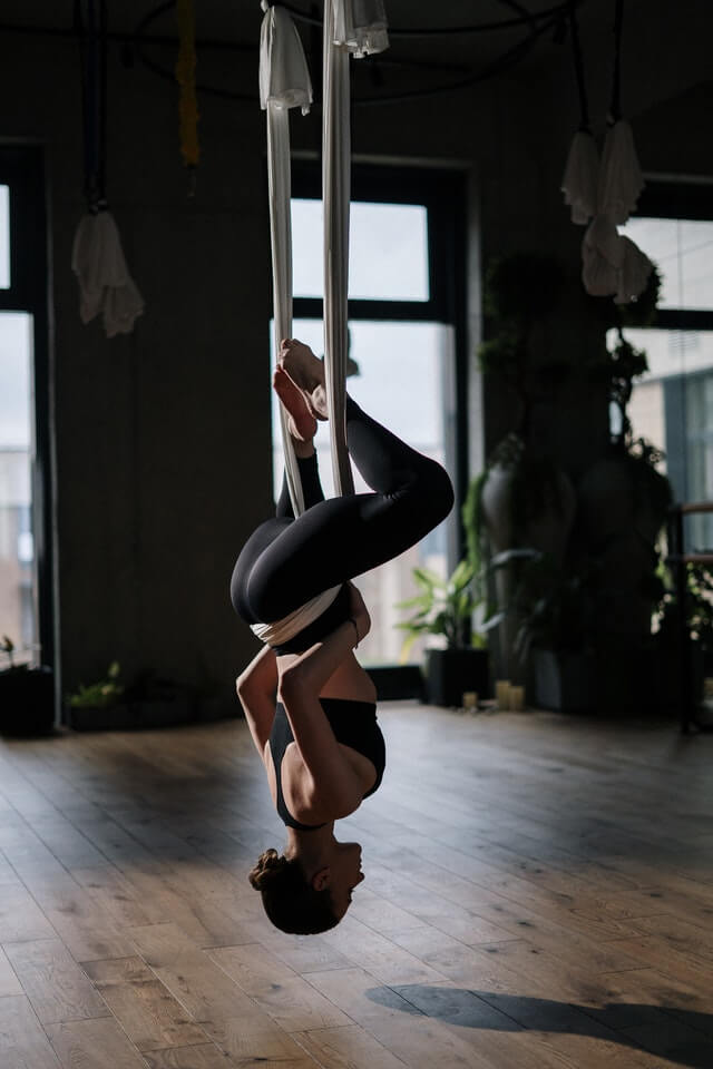 girl hanging from the ceiling in yoga class upside down