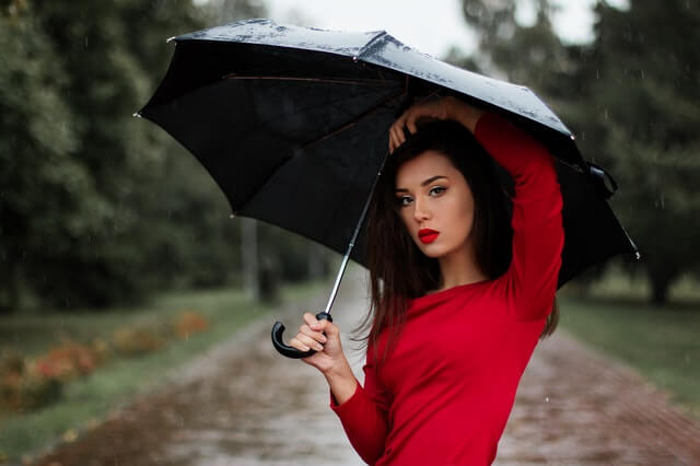 girl in red blouse wearing cosmetics with a black umbrella