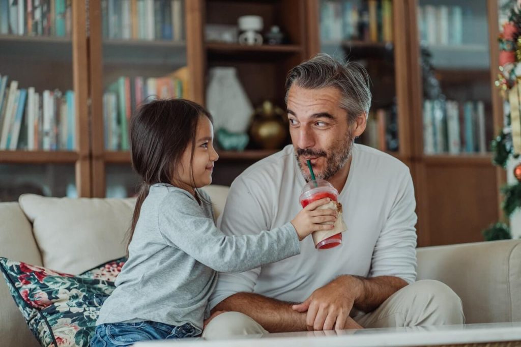 father and daughter sharing a smoothie 