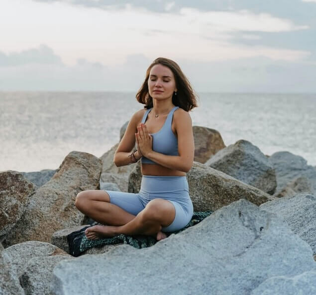 woman doing yoga and meditation by the beach