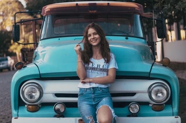 fashion, clothes, woman with ripped jeans in front of blue truck