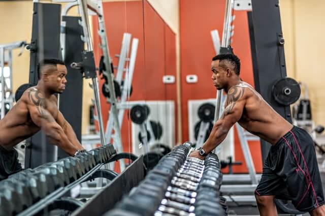 man at the gym looking in the mirror and working out with dumbells