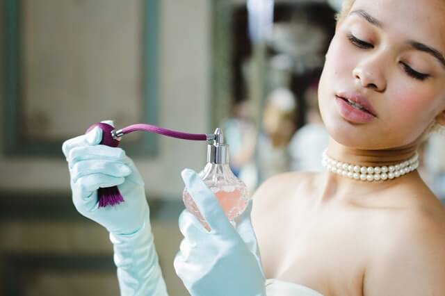 girl with pearls trying on perfume