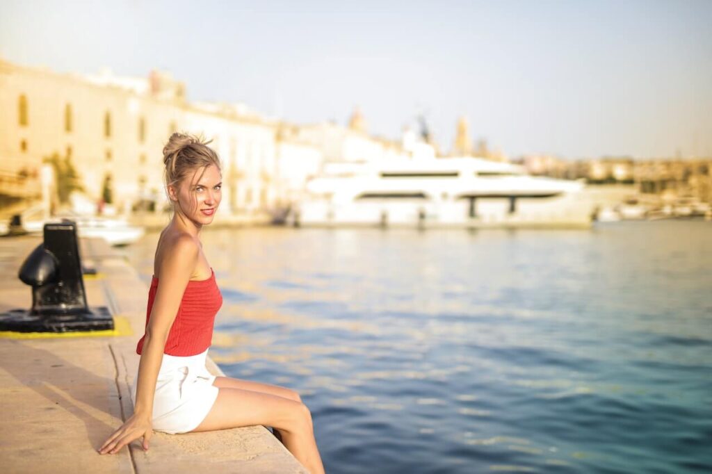 woman by the beach wearing a red top and white shorts