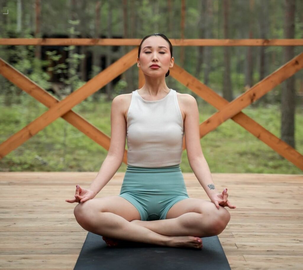 asian woman meditating in the lotus position on her porch